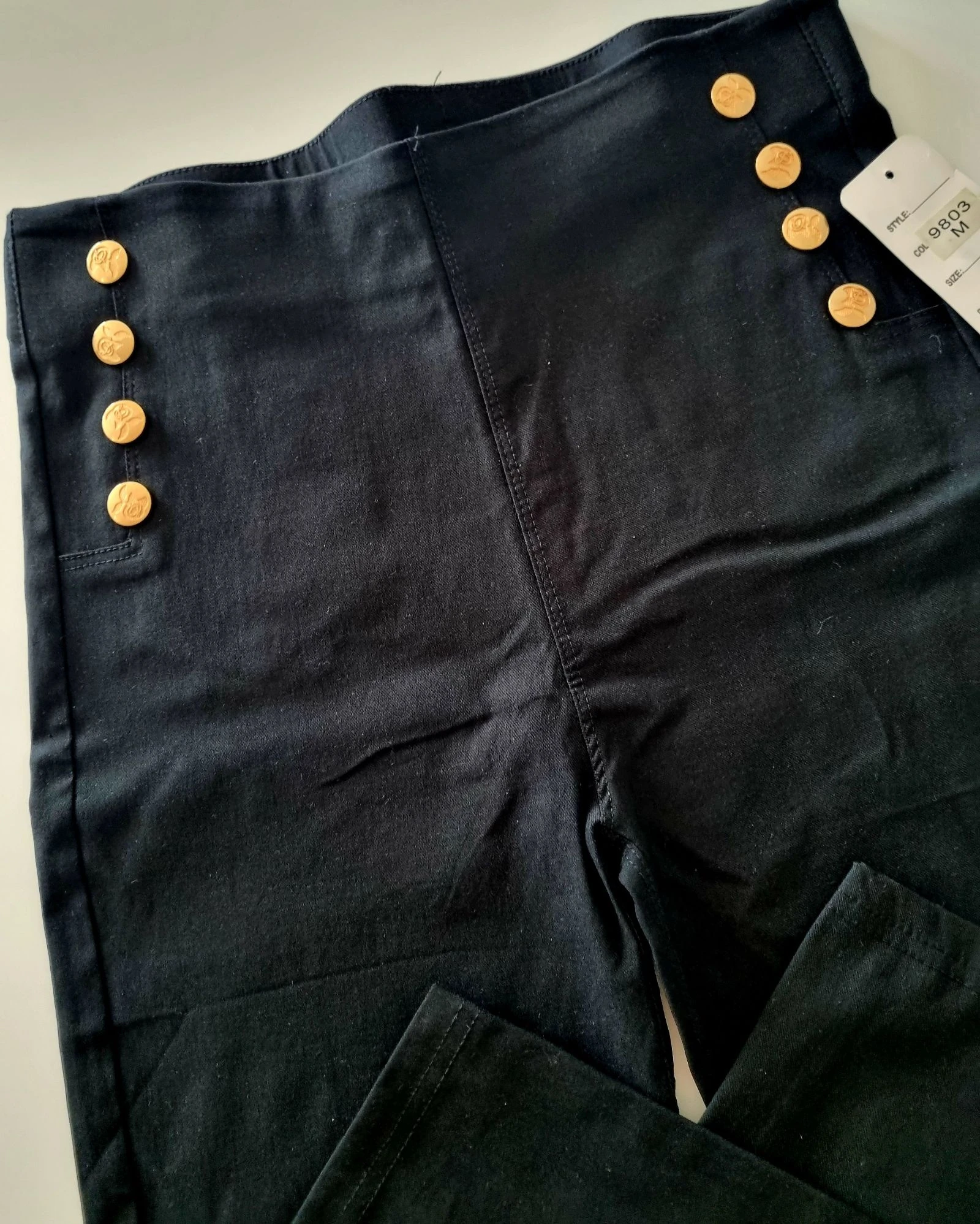 Calças/leggings pretas, com 8 botões dourados à frente. M